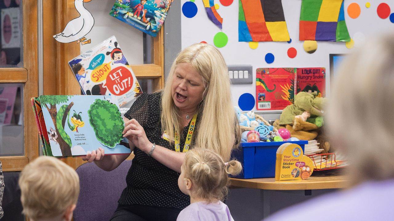 Host of a Storytime reading aloud from a picture book to toddlers