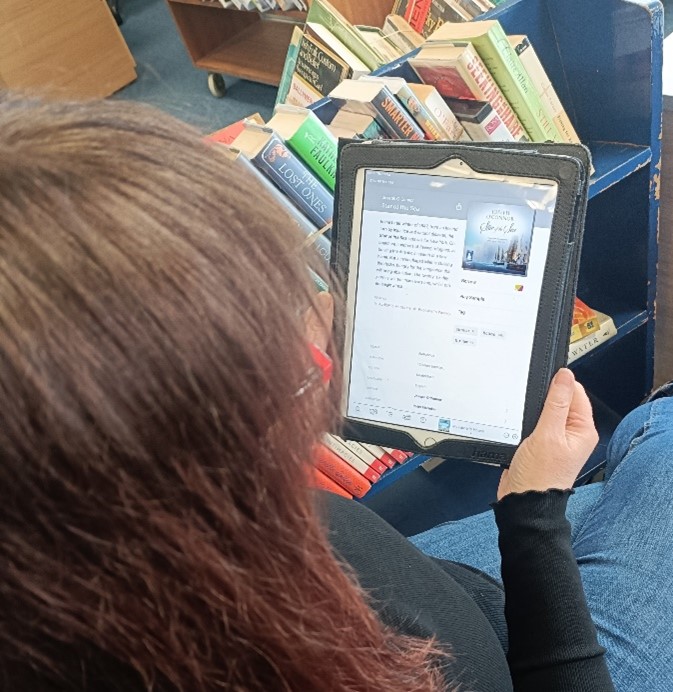 A person sitting and looking at a digital book on a tablet device