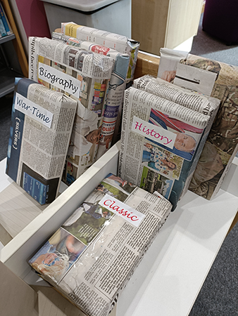 Table with a number of surprise books wrapped with only the genre as a label and no title visible