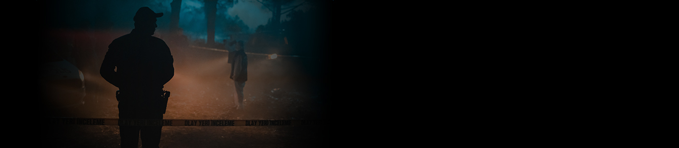 A crime scene at night in the dark with the silhouette of two people