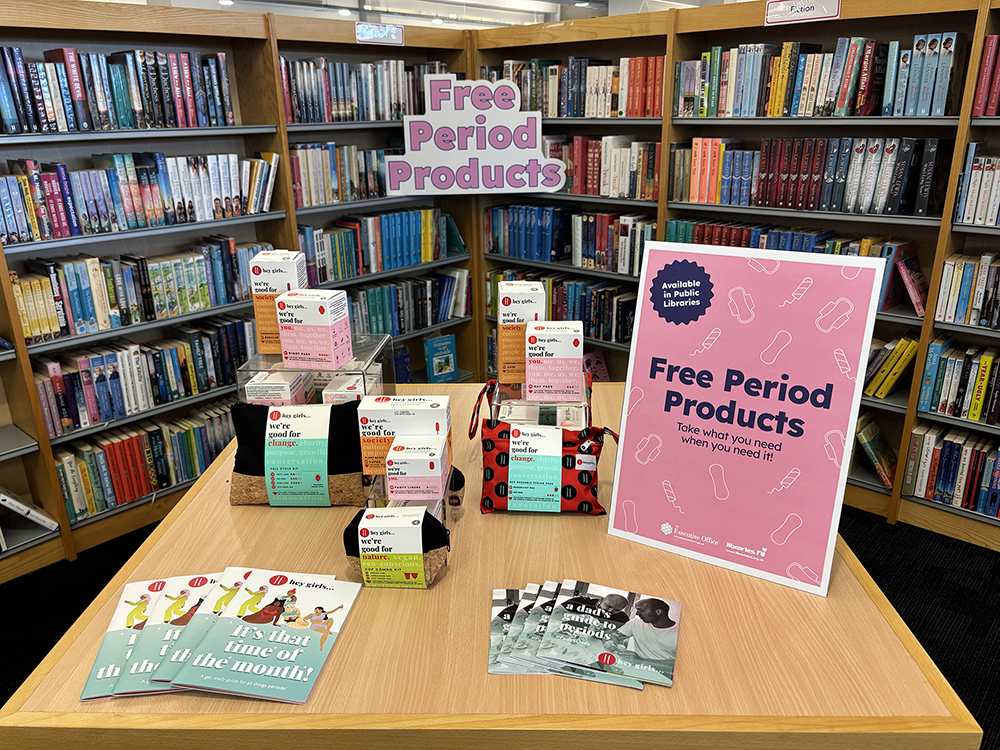 A Free Period Products display in a library including booklets and products and a poster