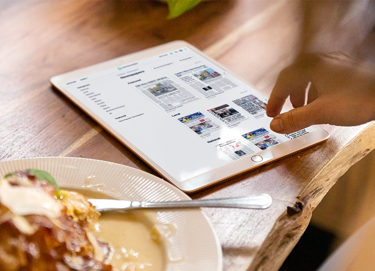 Highlight tile showing someone reading an e-Newspaper on a tablet device