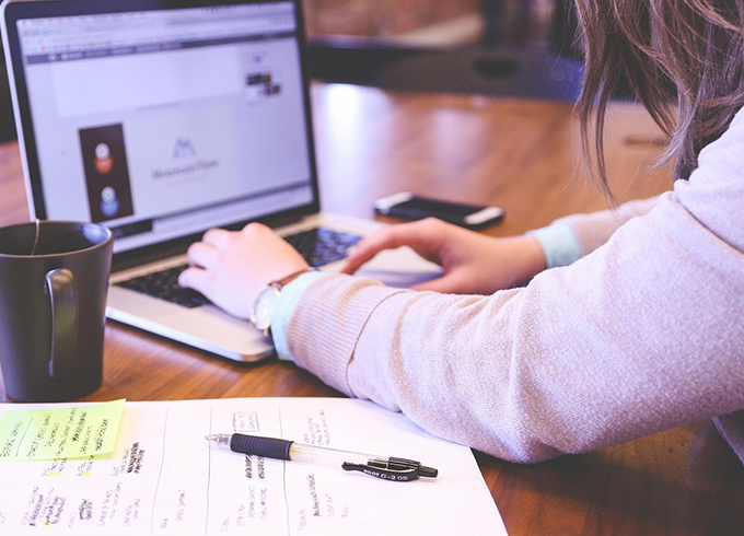 A photo of a student with their laptop and notes while studying