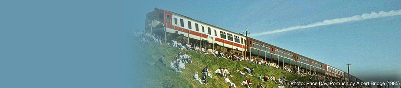 An old photo of people sitting in a field beside the rail line as a train passes by