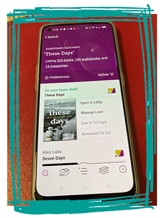Mobile phone with 'These Days' book in the Libby App showing on screen