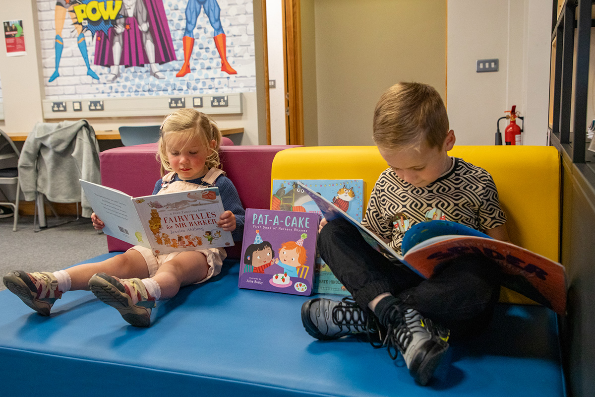 Two young children reading books in a library